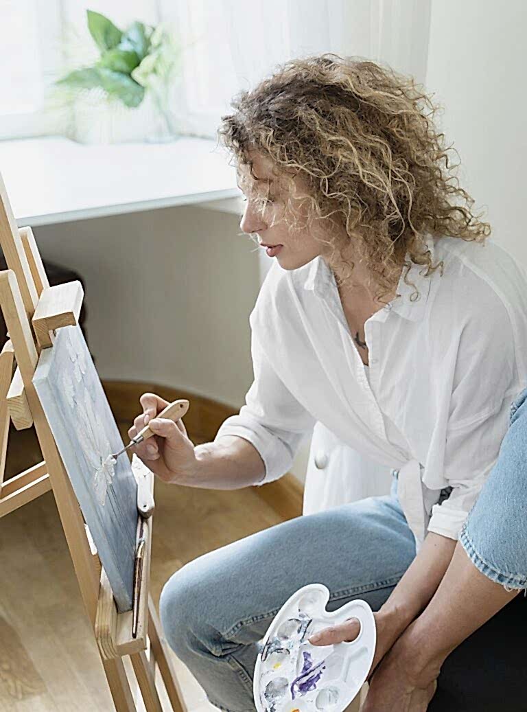 side-view-curly-haired-woman-painting-home